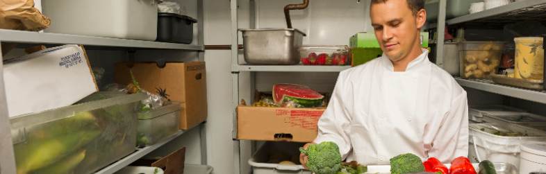Man Holding Tray Of Veggies Inside Restaurant Cooler Man Holding Tray Of Veggies Inside Restaurant Cooler